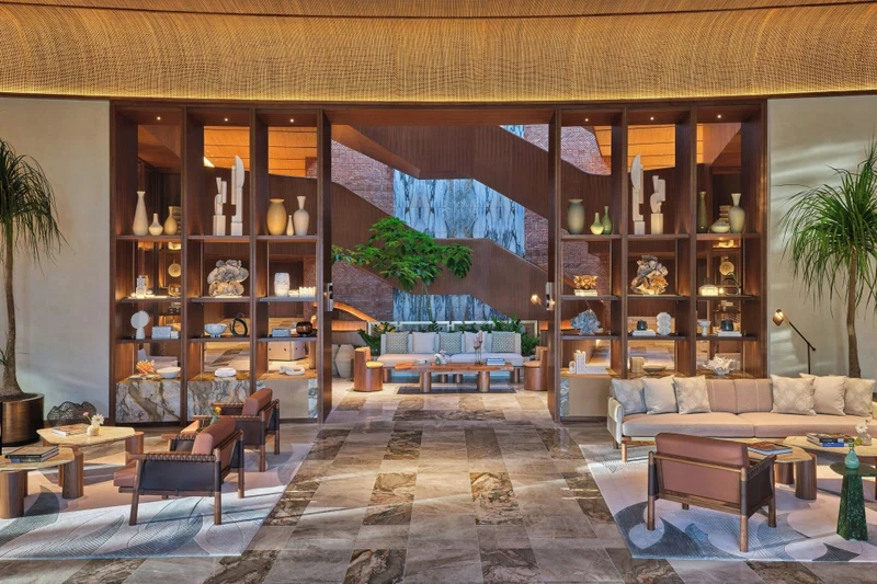 A spacious lobby with a central seating area, a staircase, and a large plant.