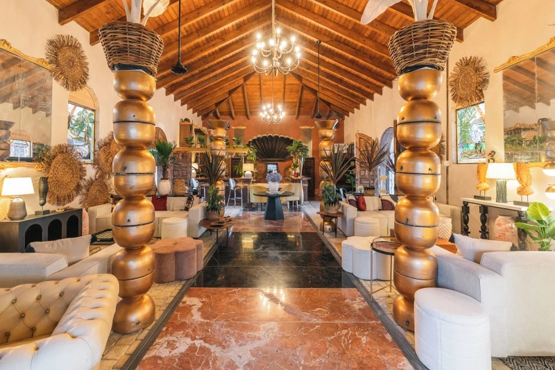 A spacious lobby with a high ceiling, a central chandelier, and a marble floor.
