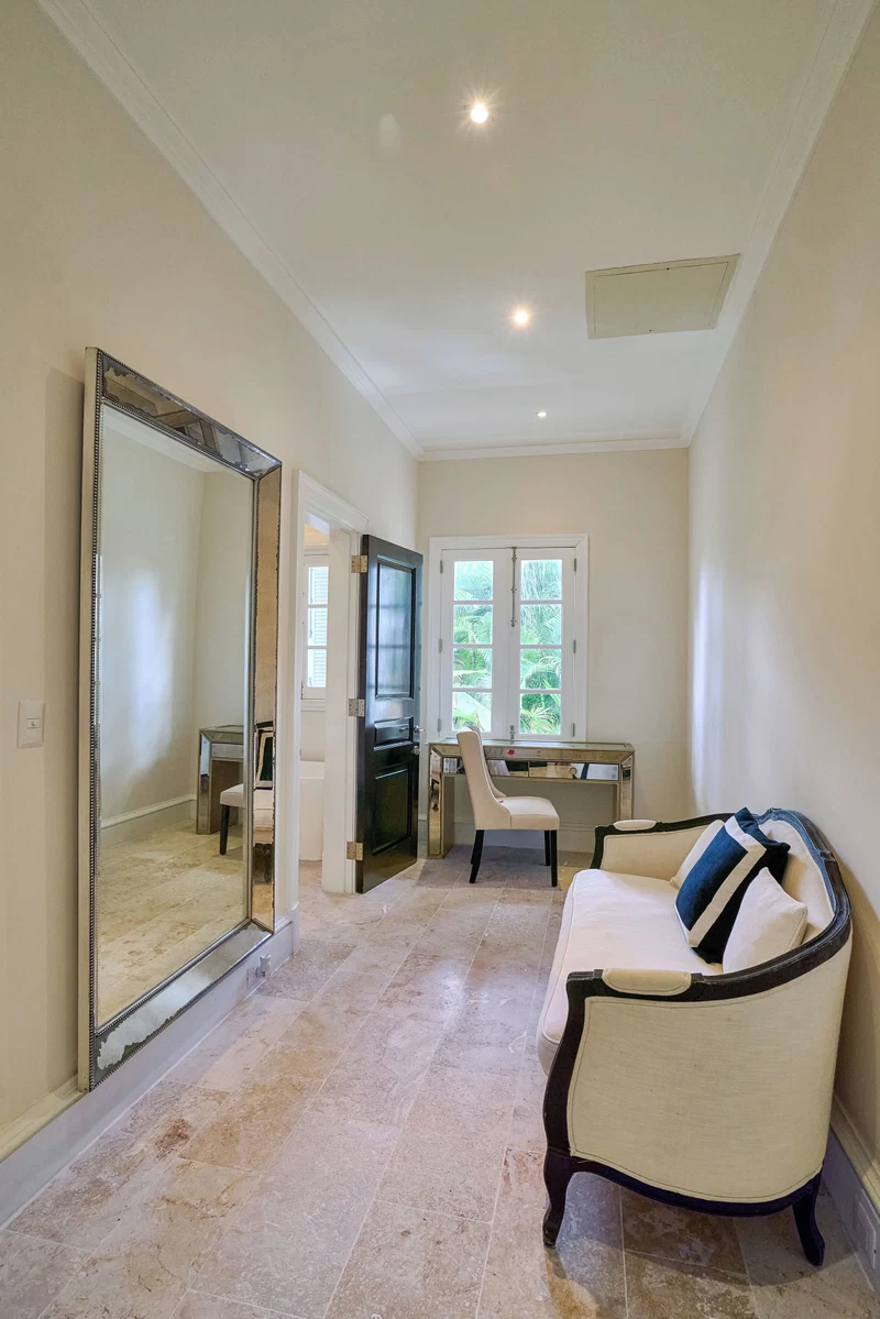 A room with a large mirror, a desk, a chair, and a sofa.