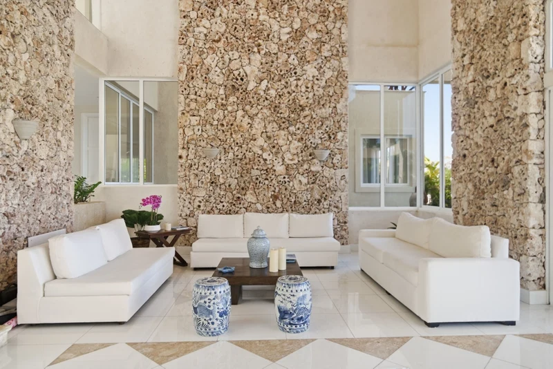 A spacious living room with a white sofa set, a coffee table, and decorative vases.