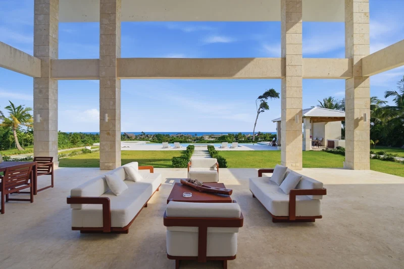 A spacious outdoor seating area with a view of a pool and ocean.