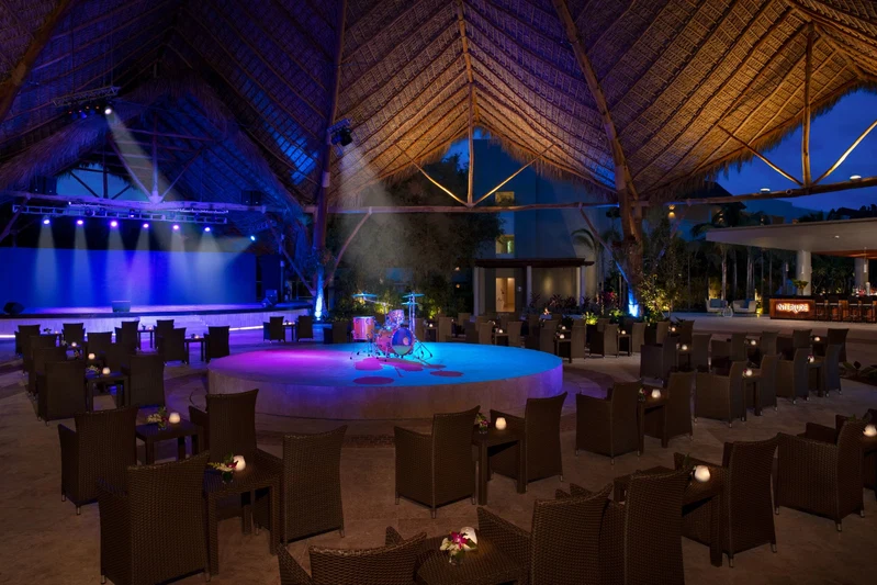 An outdoor dining area with wicker furniture and a stage for performances.