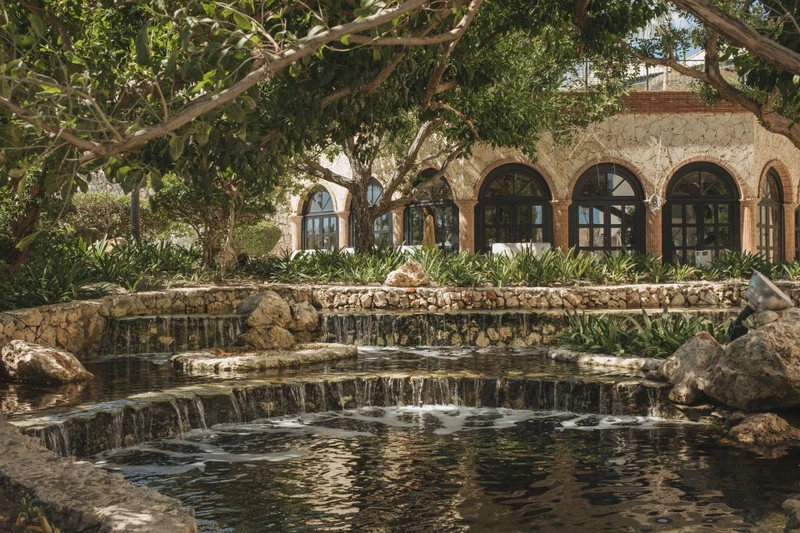 A stone building with arched windows and a water feature in front.