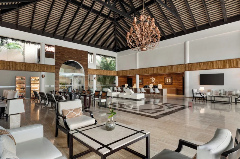 A spacious lobby with high ceilings, a chandelier, and a variety of seating arrangements including sofas and chairs.