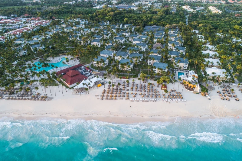 An aerial view of a resort with multiple buildings, a beach, and a swimming pool.