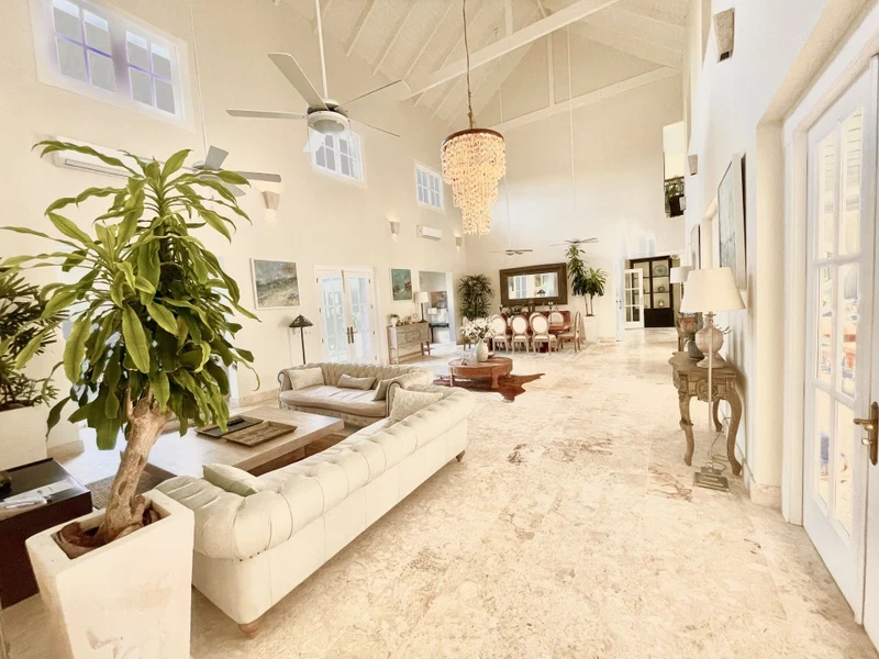 A spacious living room with a large white sofa, a dining area with a chandelier, and multiple ceiling fans.