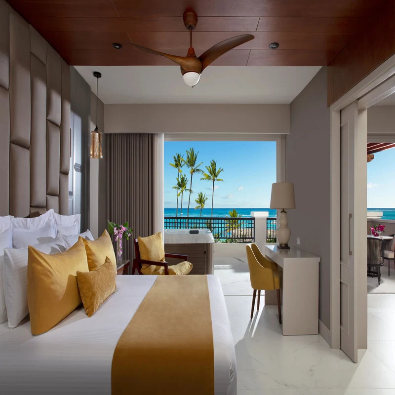 A hotel room with a bed, a desk, and a view of the ocean.