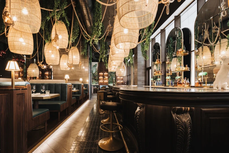 A bar area with wicker hanging lights, cushioned seating, and a polished bar counter.