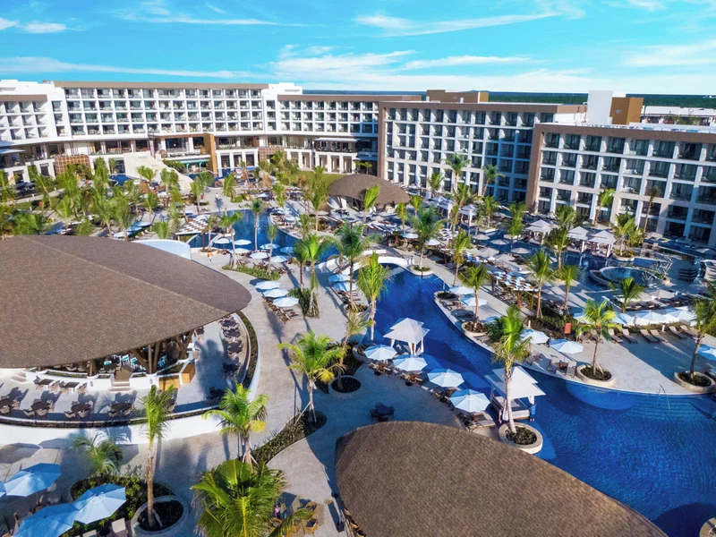 A resort with multiple swimming pools, palm trees, and a large building with numerous balconies.