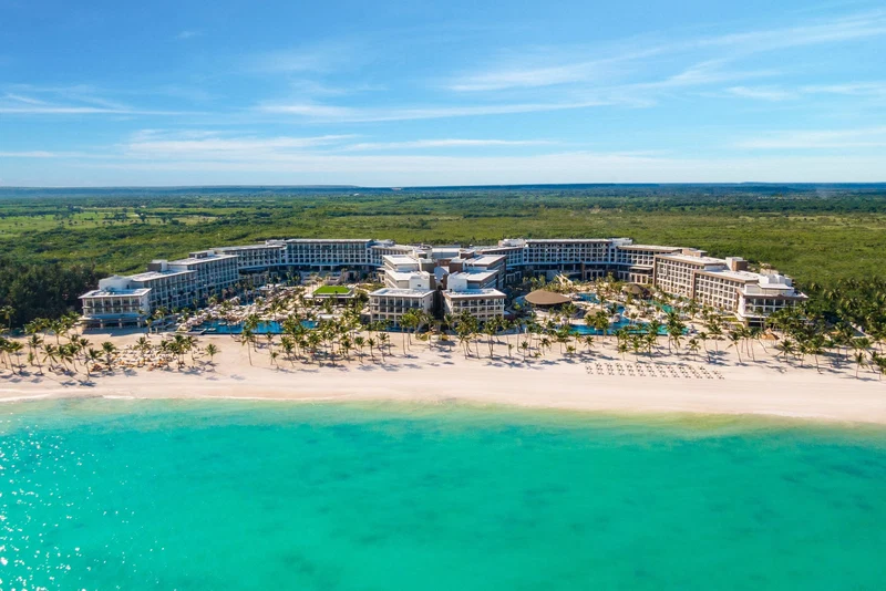 A resort with a curved building, a beach, and a clear view of the ocean.