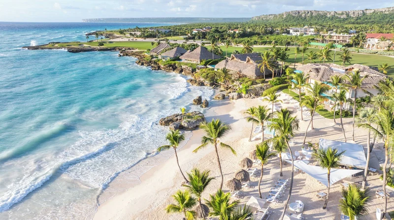 A coastal resort with beachfront accommodations, palm trees, and a golf course.