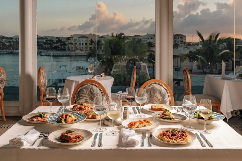 A table set for dinner with a view of a harbor and buildings.
