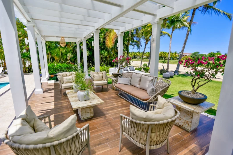 An outdoor patio with wicker furniture, a cushioned bench, and a potted plant.