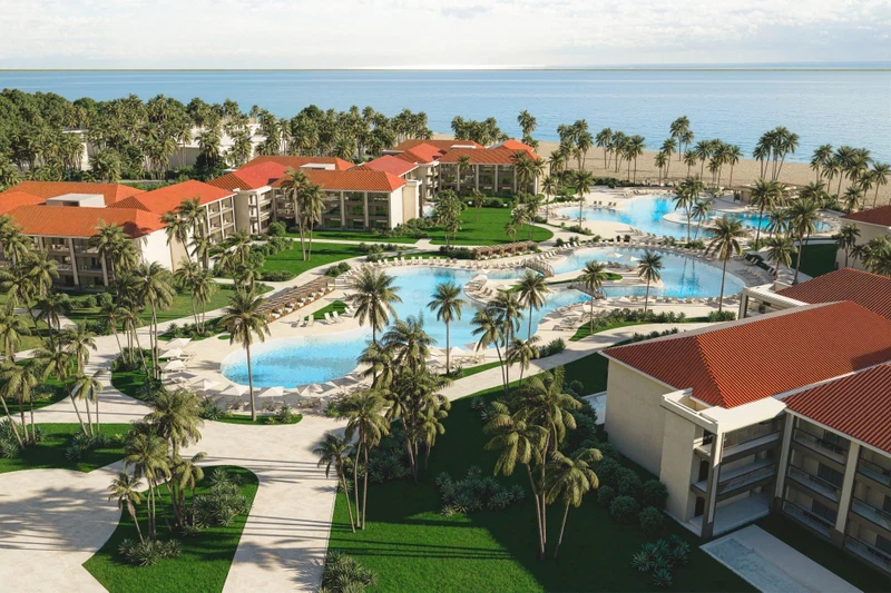 A resort with multiple swimming pools, palm trees, and beachfront views.