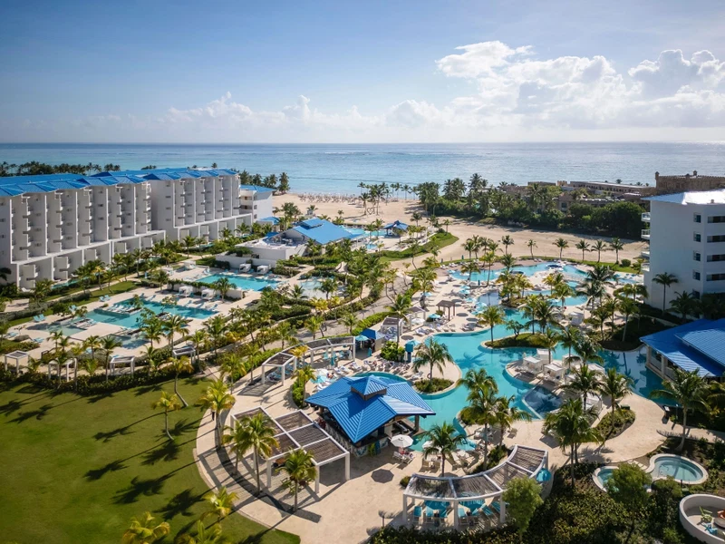 A resort with multiple swimming pools, a beach, and a view of the ocean.