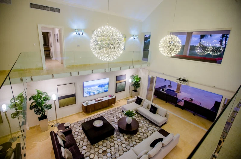 A spacious living area with a high ceiling, large windows, and modern decor.