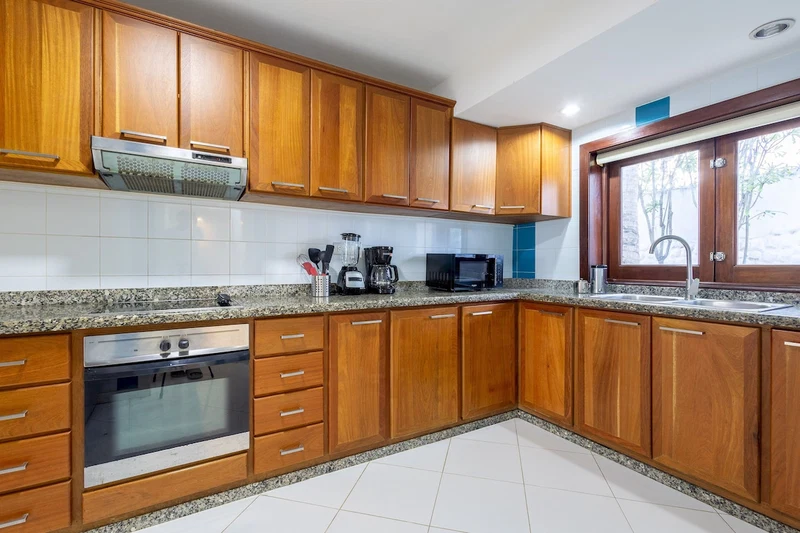 A kitchen with wooden cabinets, a built-in oven, a microwave, and a sink.