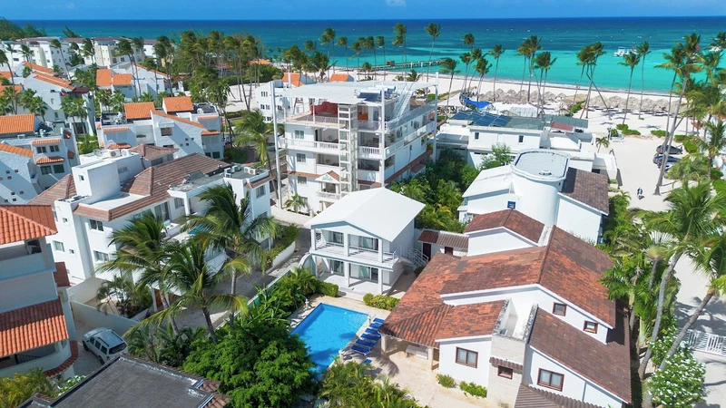 A resort with multiple buildings, a swimming pool, and a beach view.