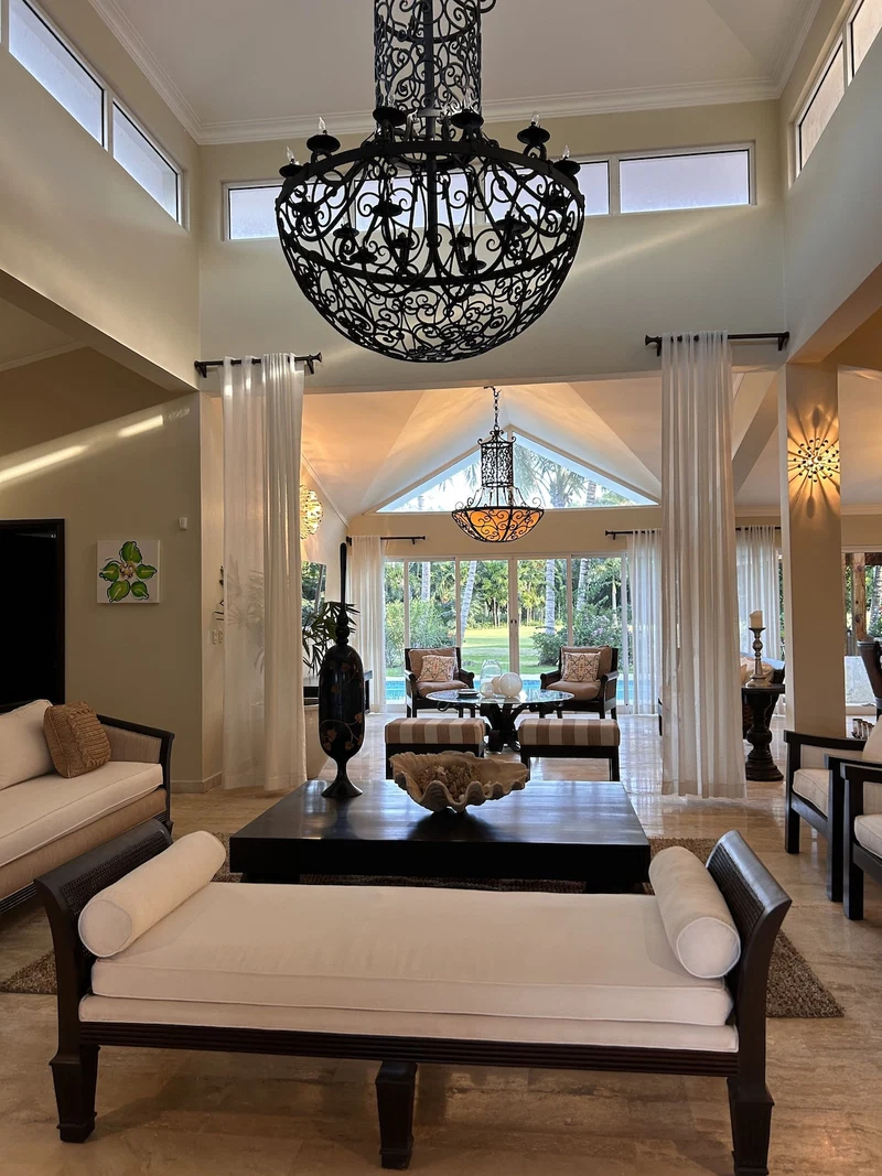 A spacious living room with a high ceiling, two sofas, a coffee table, and a chandelier.
