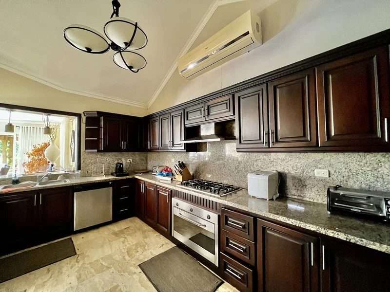 A modern kitchen with dark wooden cabinets, a granite countertop, a gas stove, a built-in oven, and a microwave.