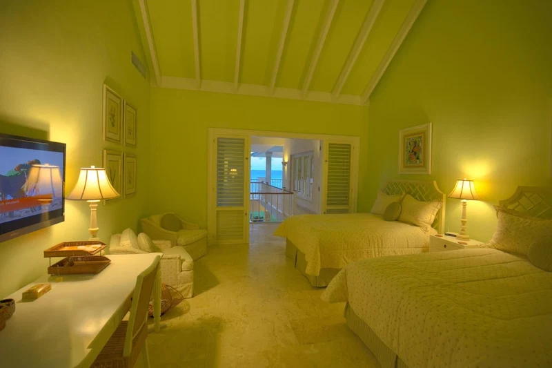 A hotel room with two beds, a TV, a desk, and a balcony with a view.