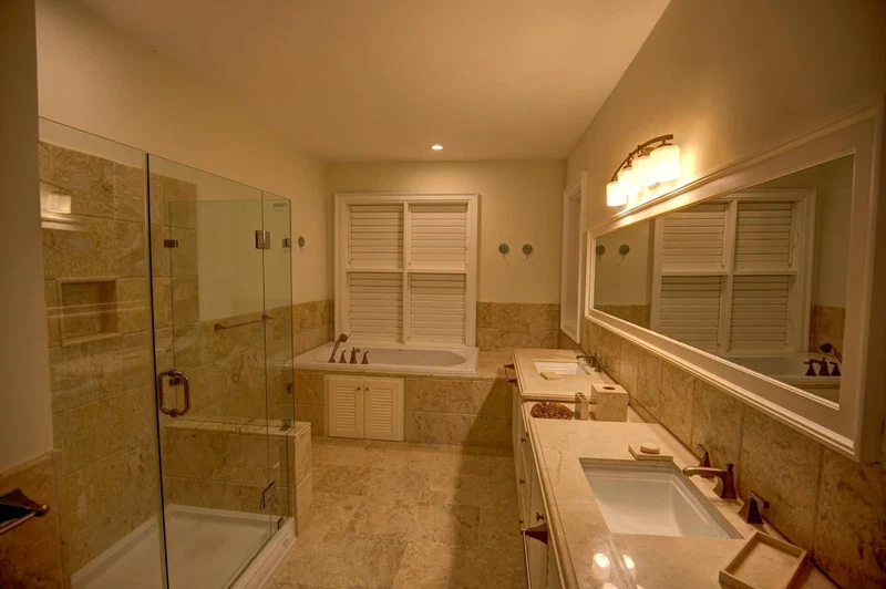 A modern bathroom with a glass-enclosed shower, a large bathtub, and two sinks.