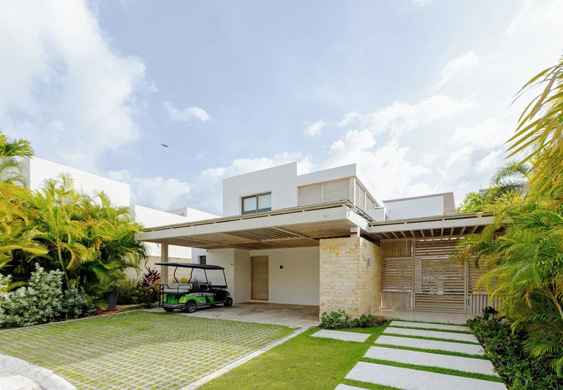 A modern house with a covered garage, a green golf cart, and a well-maintained lawn.