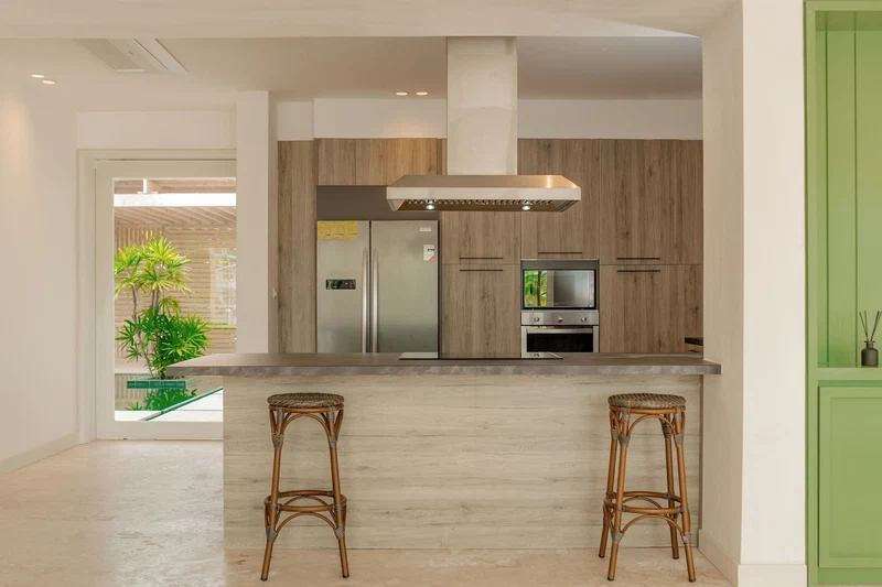 A modern kitchen with wooden cabinets, stainless steel appliances, and a central island with two bar stools.