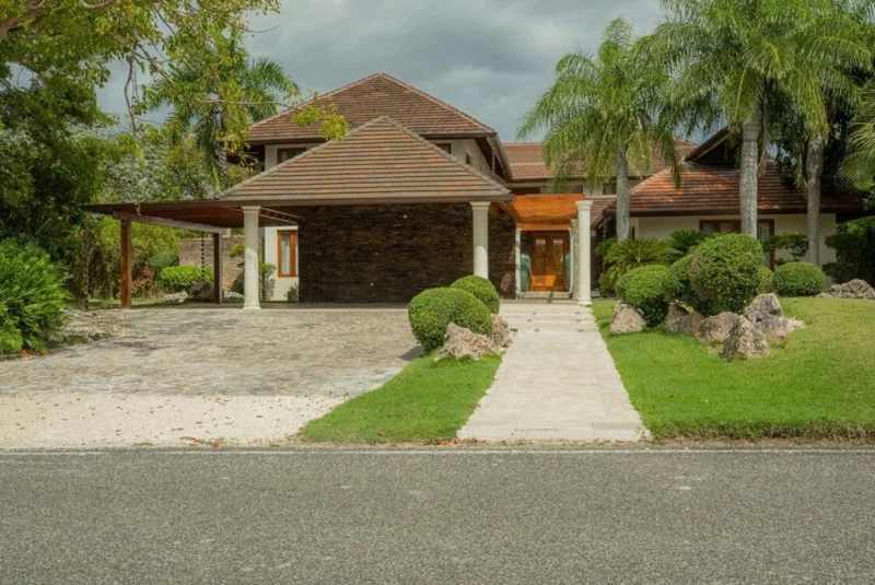 A two-story house with a stone facade, a covered porch, and a well-maintained lawn.