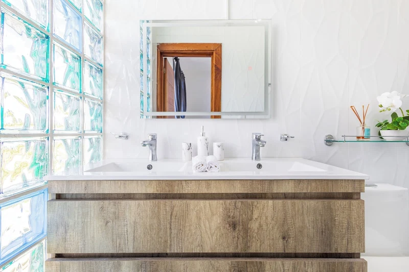 A bathroom with a wooden vanity, a large mirror, and a glass shower enclosure.