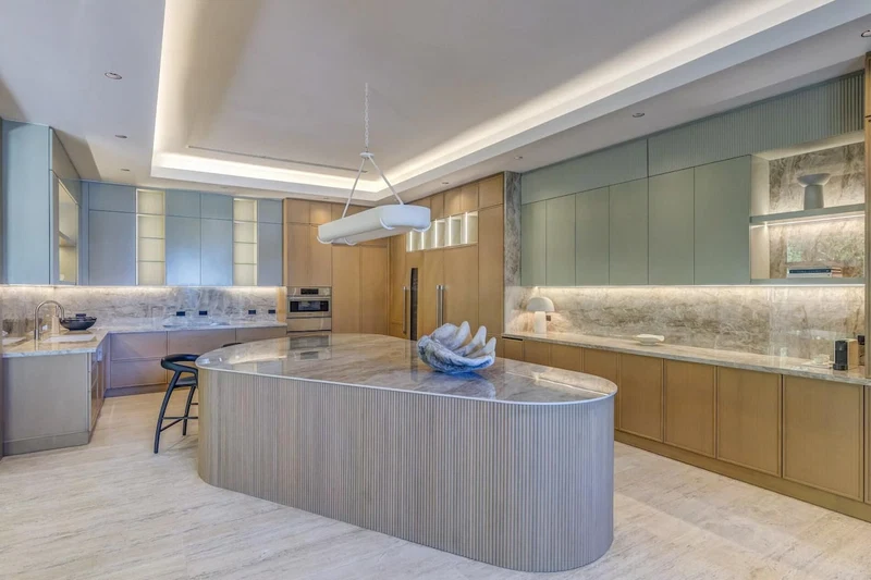 A modern kitchen with a central island, built-in appliances, and a unique light fixture.