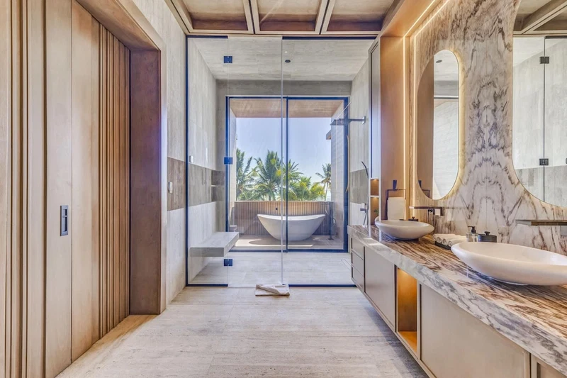 A modern bathroom with a large bathtub, a marble vanity, and a glass-enclosed shower area.