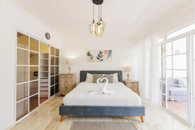 A bedroom with a bed, bedside tables, a wardrobe, and a large window.