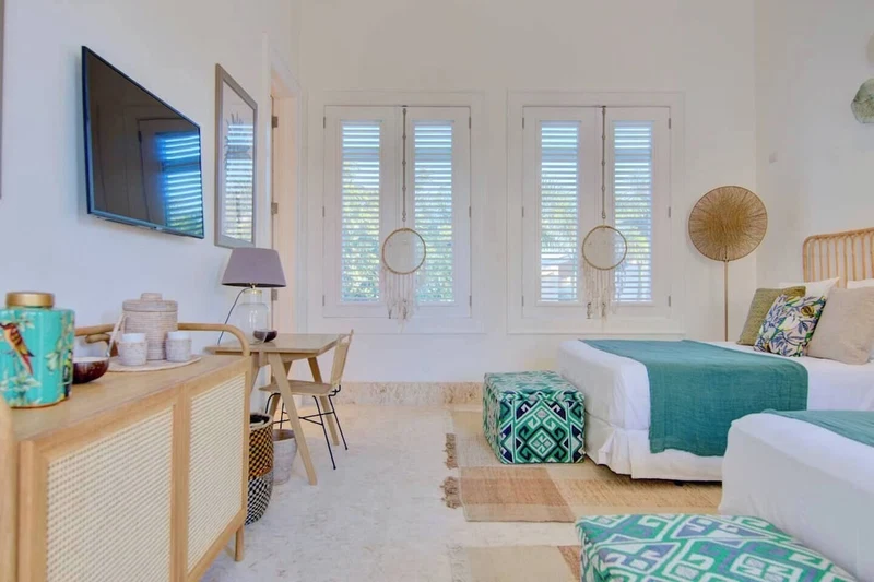 A bedroom with a bed, bedside tables, a desk, a chair, and a TV mounted on the wall.