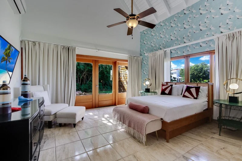 A spacious bedroom with a large bed, a sitting area, and a view of the outdoors.