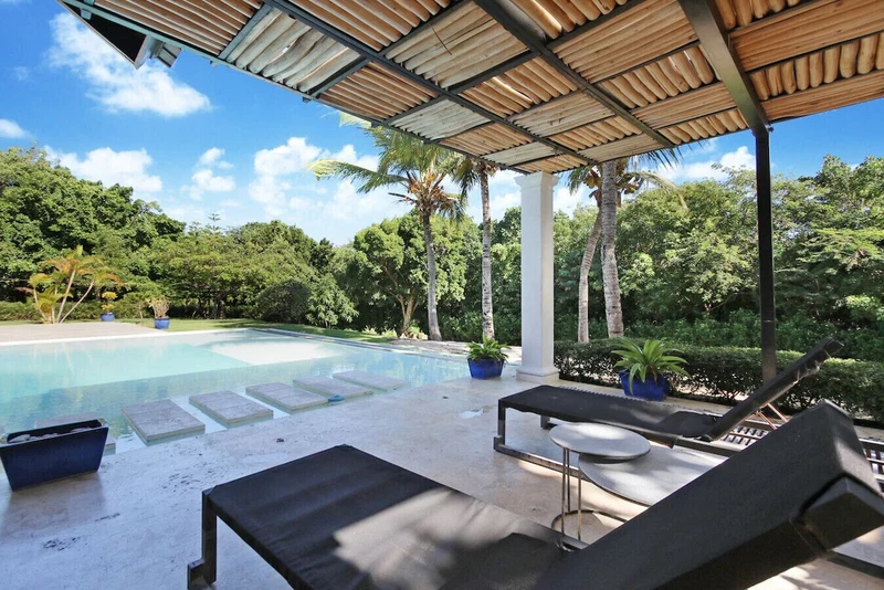 A pool area with lounge chairs, a covered patio, and a clear view of the pool.
