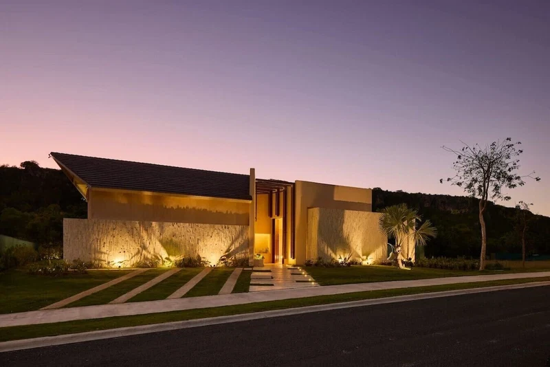 A modern house with a sloped roof, a large entrance, and a well-lit exterior.