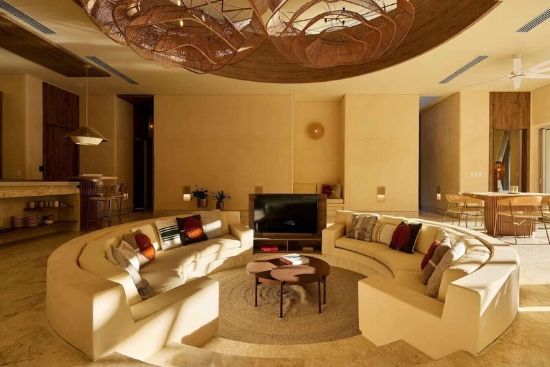 A modern living room with a curved sofa set, a flat-screen TV, and a unique ceiling light fixture.