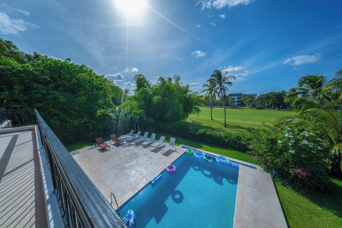 A swimming pool with lounge chairs and a view of a golf course.