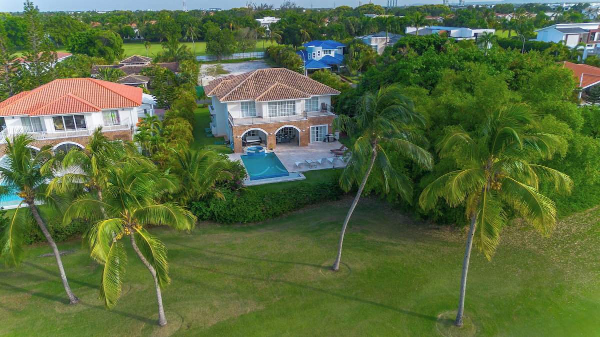 A residential property with a swimming pool, multiple houses, and lush greenery.