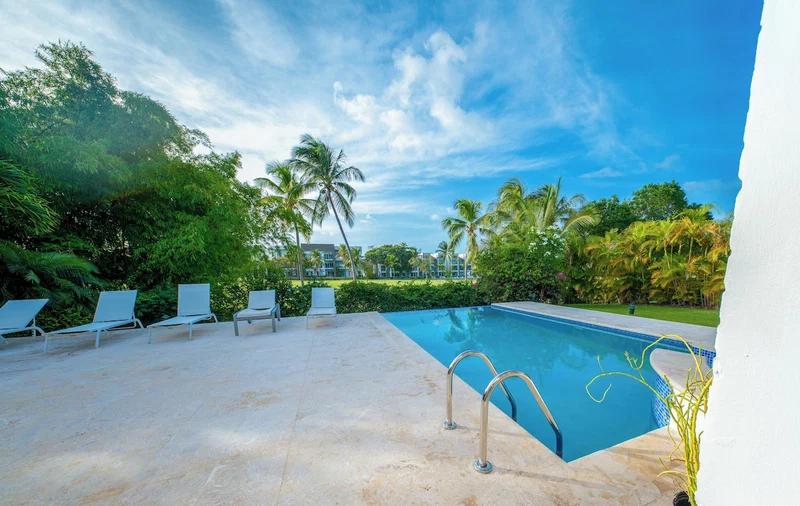 A swimming pool with lounge chairs and palm trees.