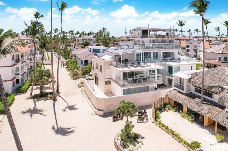 A modern resort with multiple buildings, a central courtyard, and palm trees.