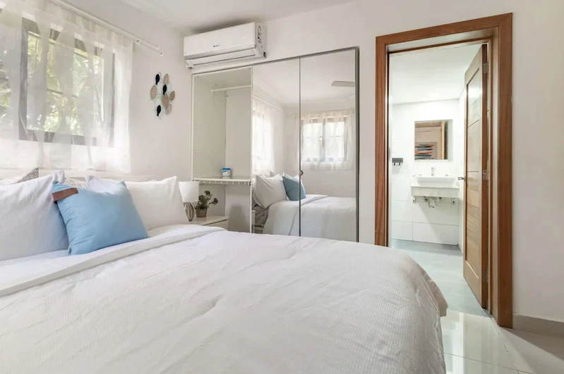 A hotel room with a large bed, a bedside table, a mirror, and a wardrobe.