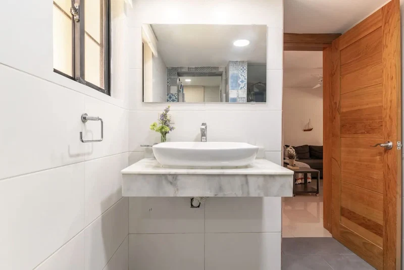 A bathroom with a white sink, a mirror, and a wooden door.