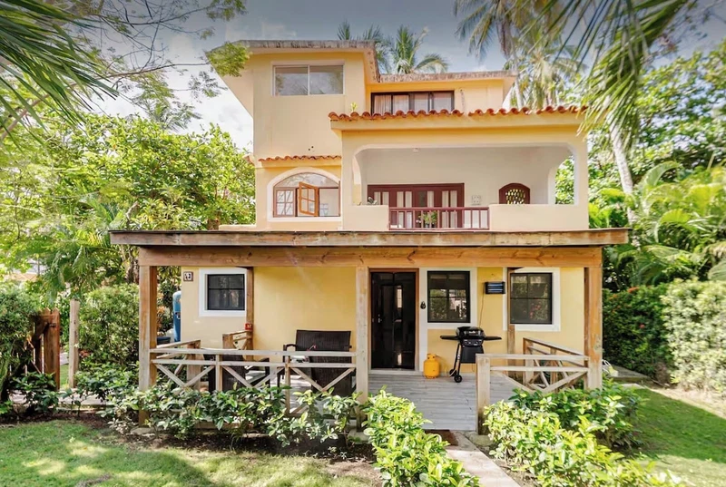 A two-story house with a balcony, a porch with wooden railings, and a small garden area.