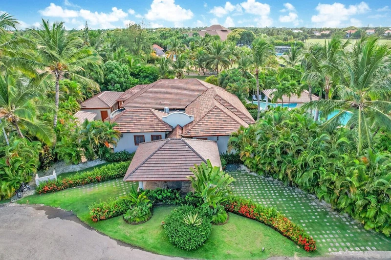 A large house surrounded by lush greenery and palm trees.