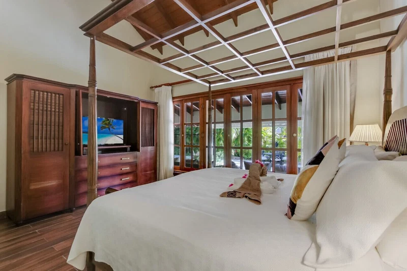 A hotel room with a large bed, wooden wardrobe, and a television.