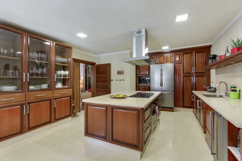 A kitchen with wooden cabinets, a central island, stainless steel appliances, and a built-in oven.