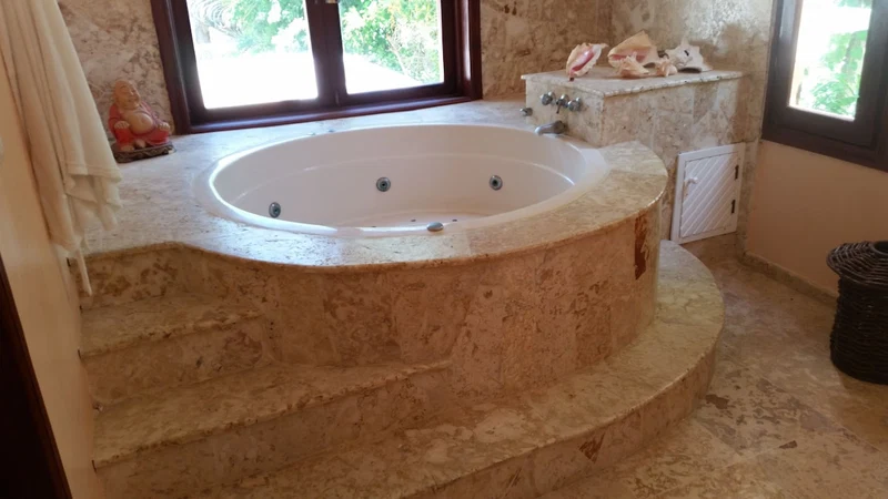 A bathroom with a freestanding bathtub, a window, and a marble countertop.