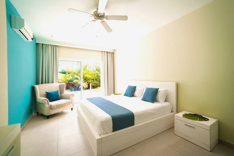 A bedroom with a bed, a chair, a nightstand, and a ceiling fan.